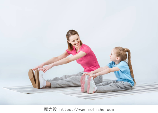瑜伽垫上拉伸的母女运动型的母亲和女儿